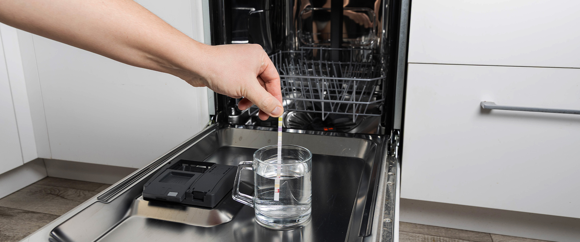 Meten van waterhardheid met teststrip bij een vaatwasser.