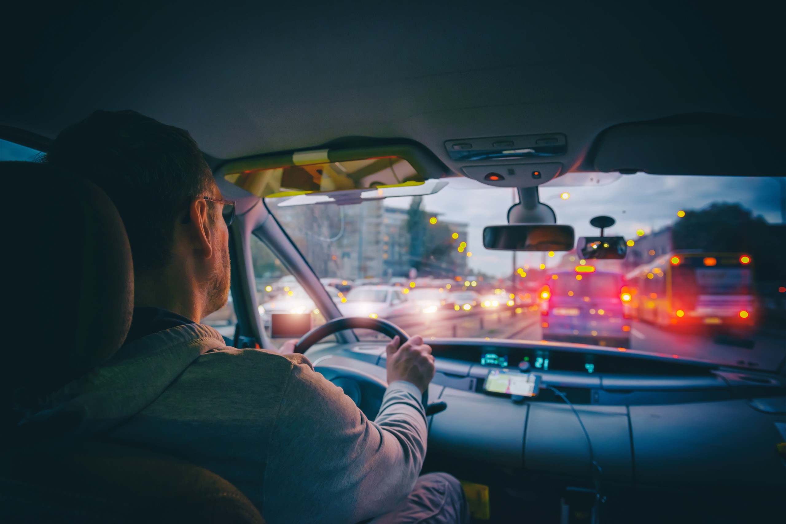 Veilig onderweg tijdens de donkere dagen Bestuurder onderweg in het verkeer tijdens de schemering met verlichting van andere voertuigen zichtbaar.
