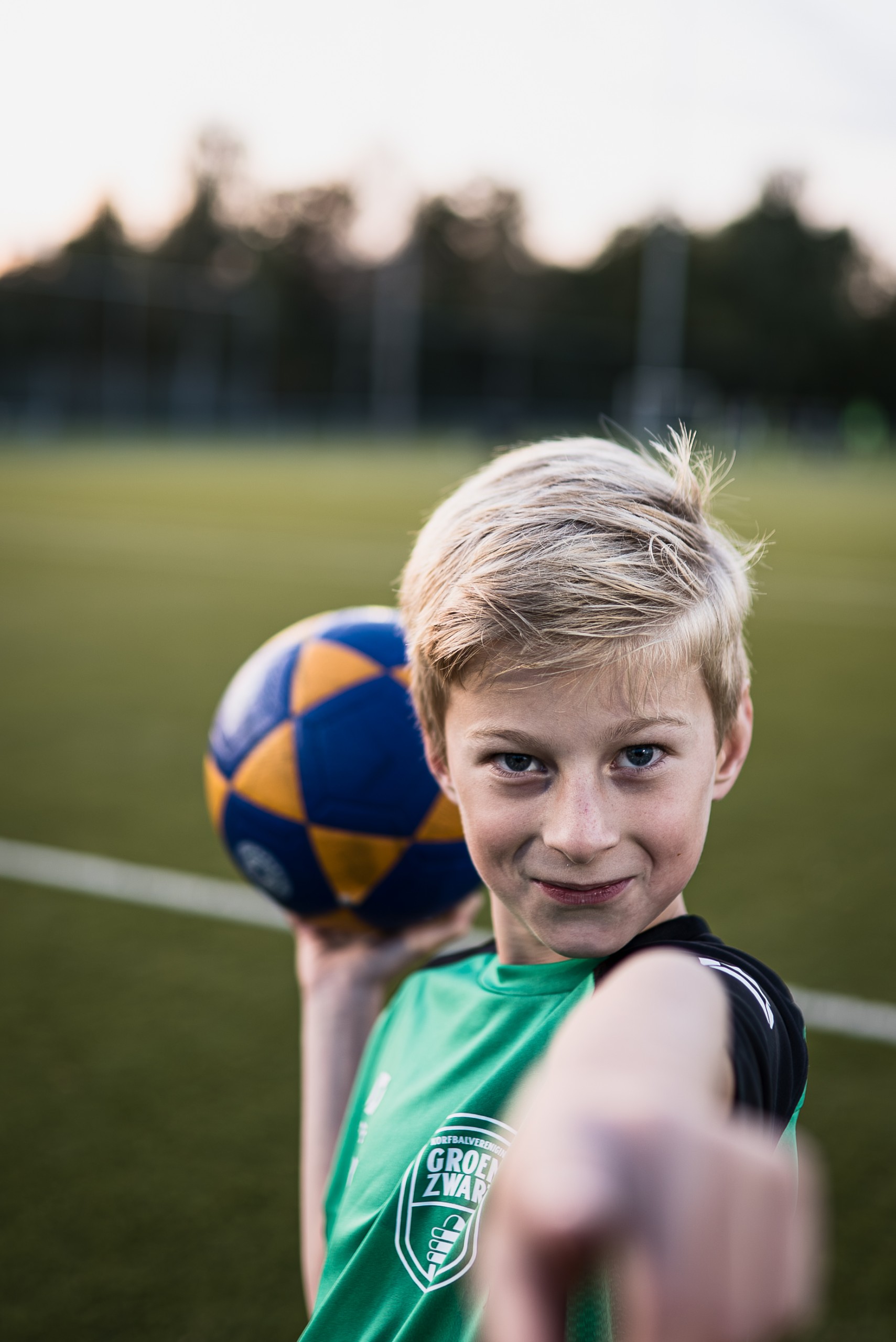 Jeugdspeler van Groen Zwart op het voetbalveld met een bal in de hand.