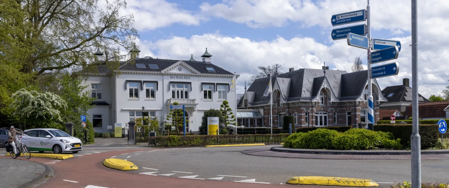 Het Witte Huis in Borne aan een rotonde met vlaggen op de voorgrond.